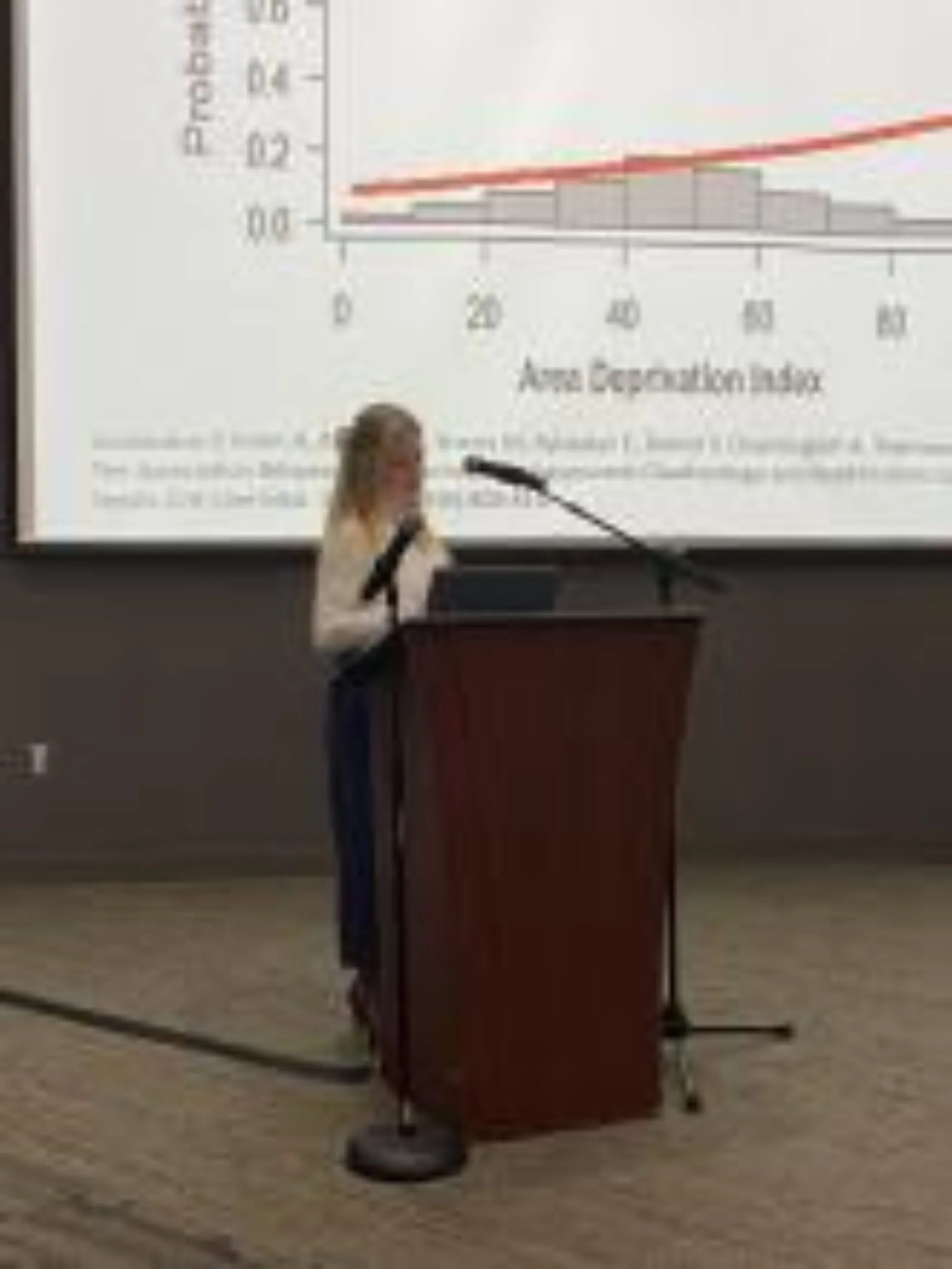 A woman at a podium presenting data