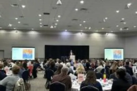 People in a conference room with a screen on the left and right