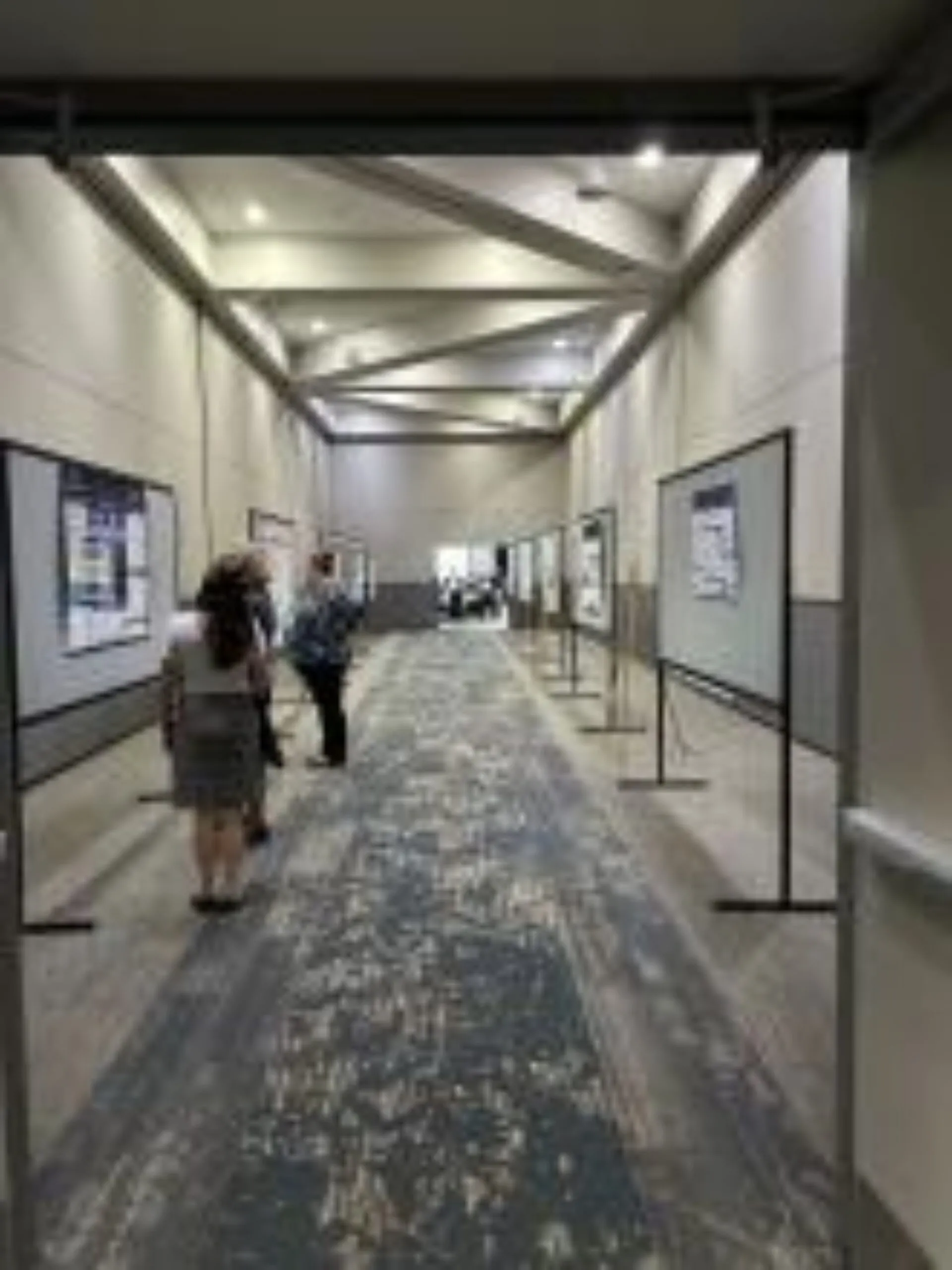 People viewing quality improvement posters in a long room