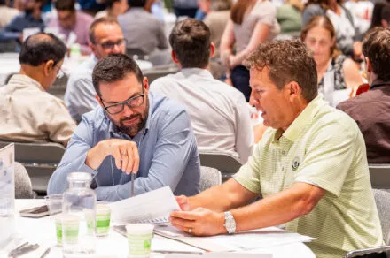 Attendees seated around a conference table during the July HMS meeting, engaged in discussion and collaboration in a professional setting.