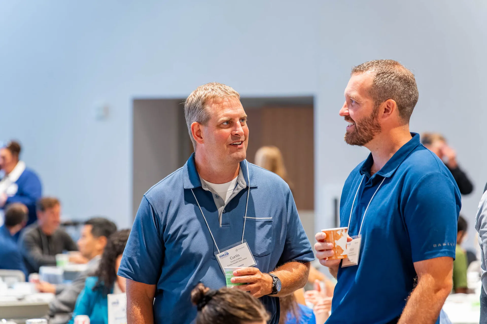 Attendees standing during the July HMS meeting, engaged in discussion and collaboration in a professional setting.