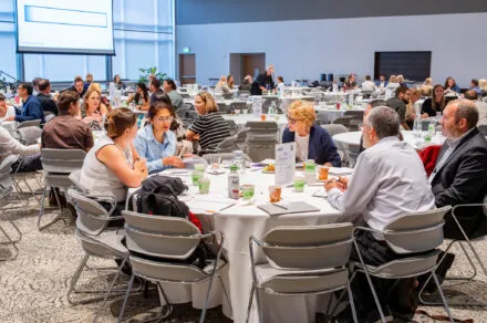 Attendees seated around a conference table during the July HMS meeting, engaged in discussion and collaboration in a professional setting.