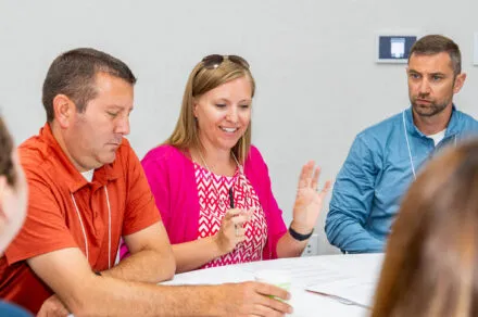 Attendees seated around a conference table during the July HMS meeting, engaged in discussion and collaboration in a professional setting.