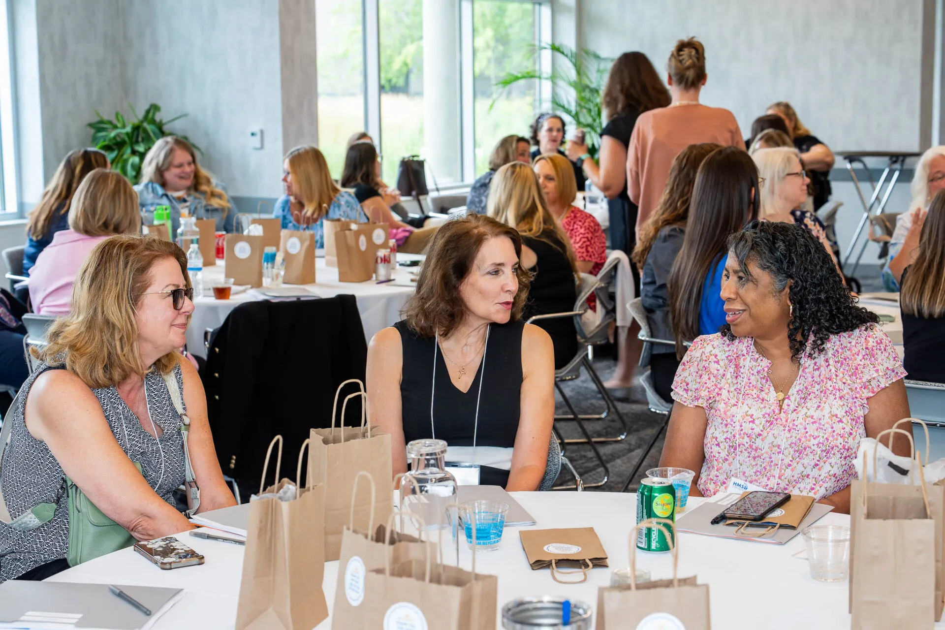 Attendees seated around a conference table during the July HMS meeting, engaged in discussion and collaboration in a professional setting.