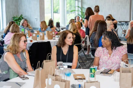 Attendees seated around a conference table during the July HMS meeting, engaged in discussion and collaboration in a professional setting.