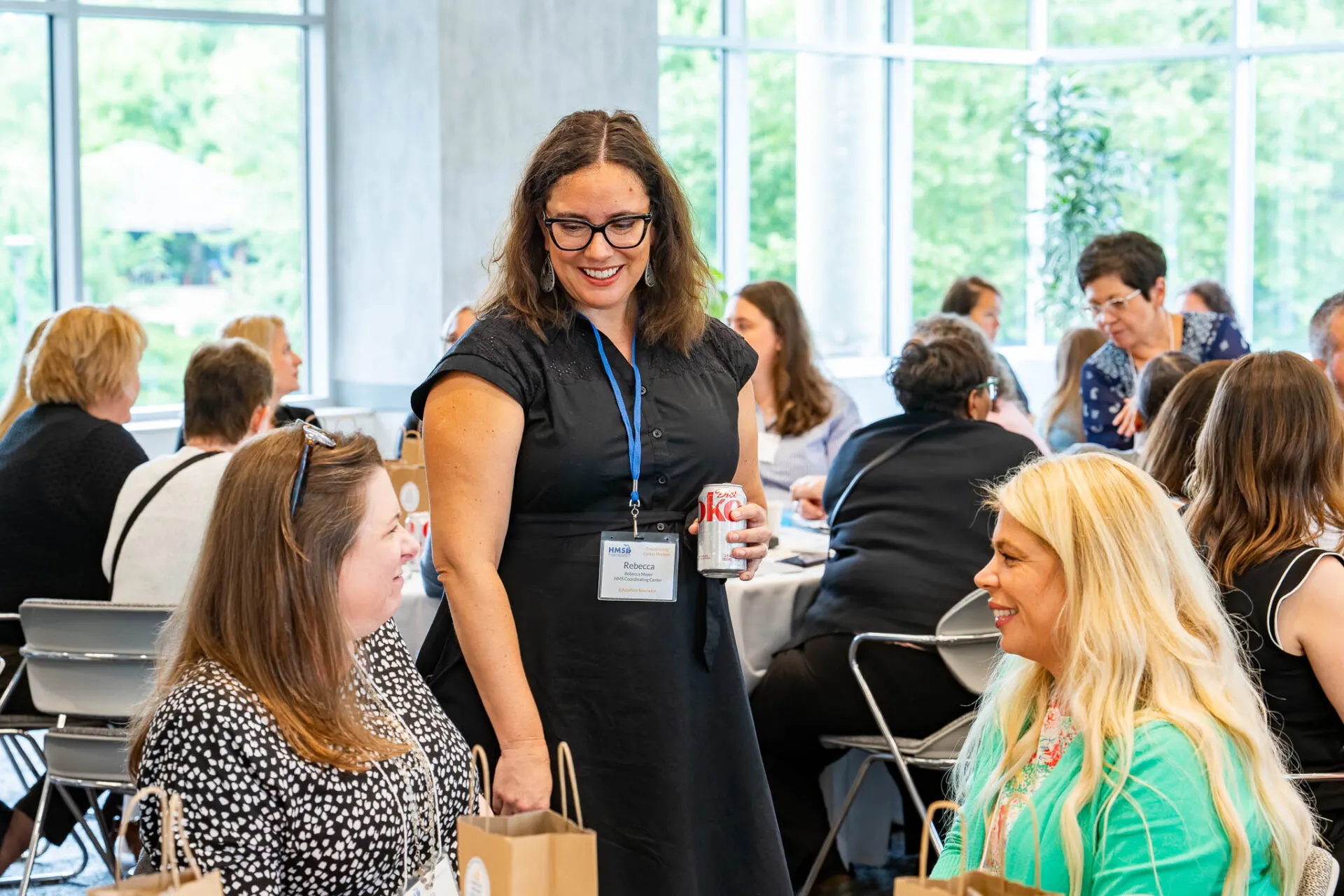 Attendees seated around a conference table during the July HMS meeting, engaged in discussion and collaboration in a professional setting.