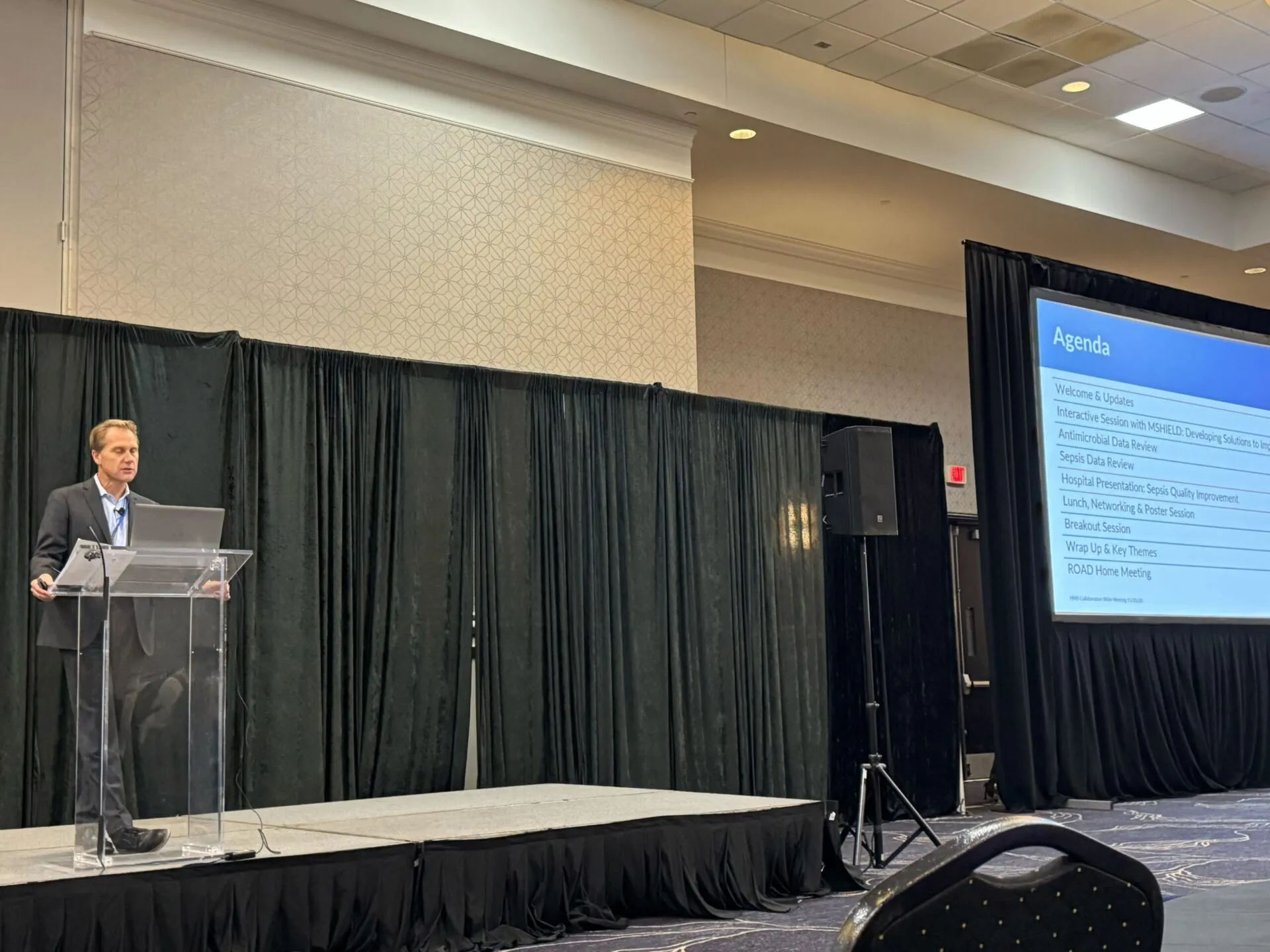 Dr. Flanders at a podium sharing the agenda for the day of the conference