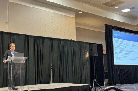 Dr. Flanders at a podium sharing the agenda for the day of the conference