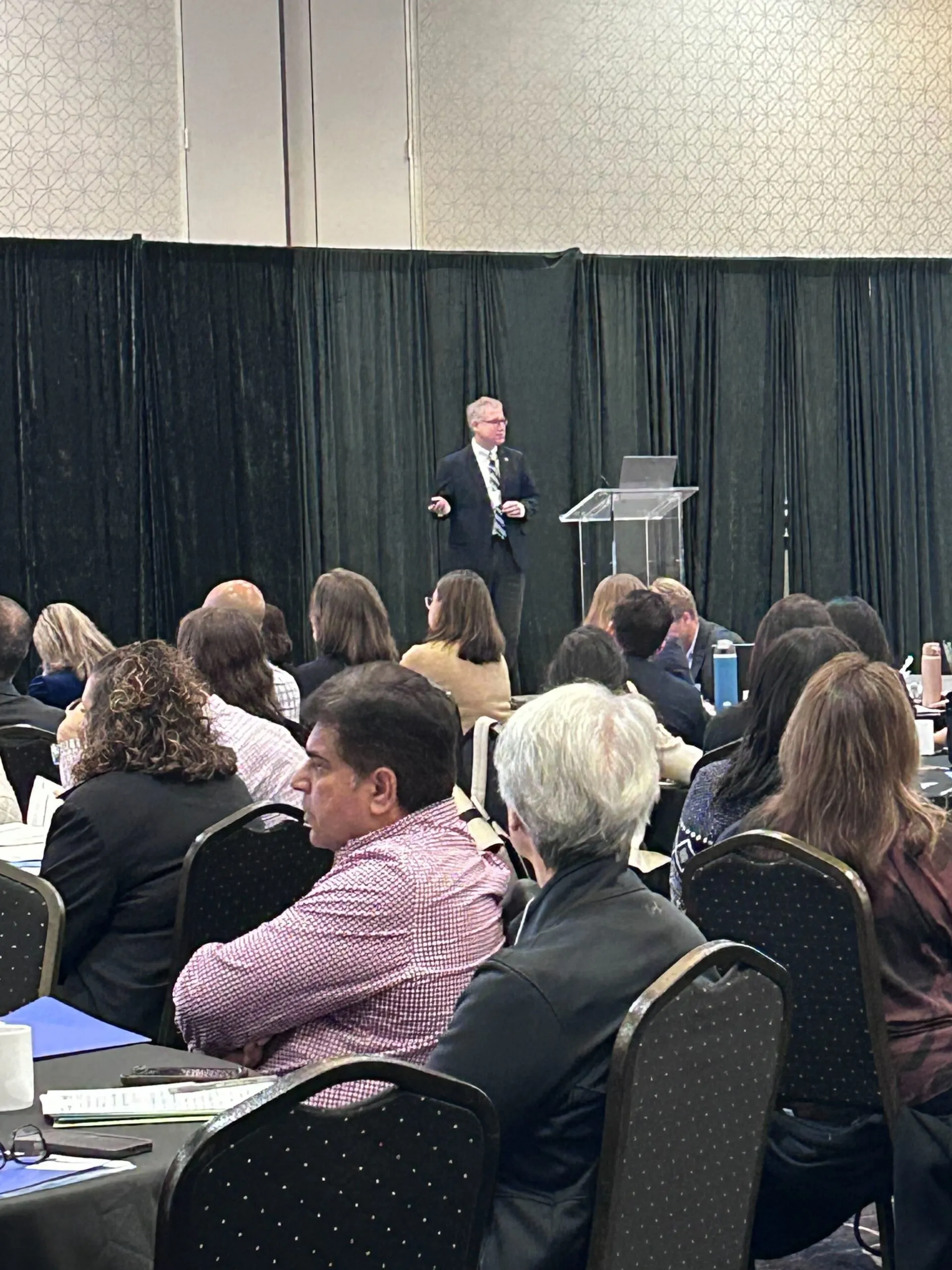 Dr. Peter Watson standing at a podium delivering a presentation
