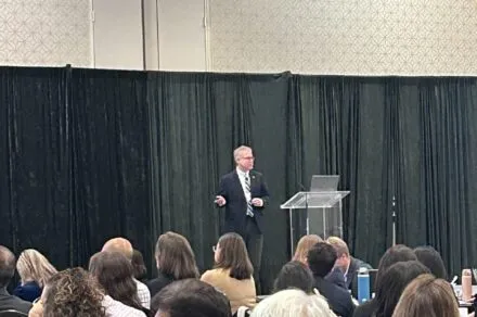 Dr. Peter Watson standing at a podium delivering a presentation