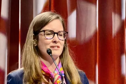 A woman standing at a podium delivering a speech.