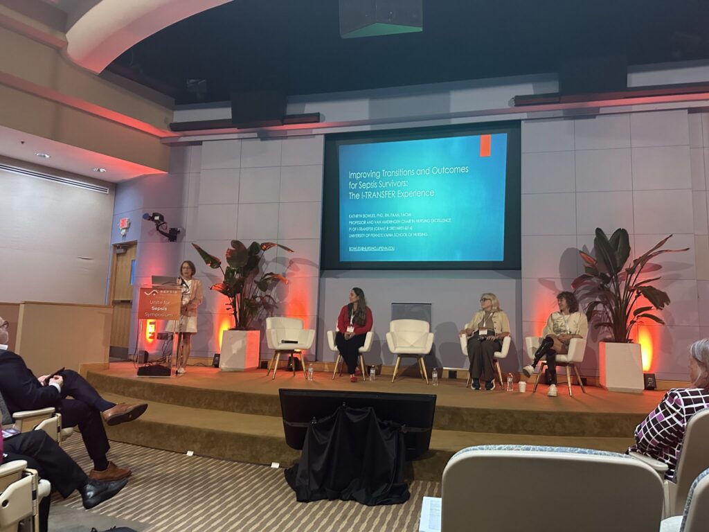 A panel discussion at the Unite for Sepsis Symposium, with a presenter at a podium and three panelists seated on stage. A projected slide behind them reads "Improving Transitions and Outcomes for Sepsis Survivors: The I-TRANSFER Experience."